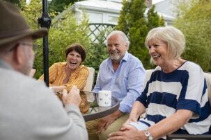 Senior friends sitting at a table outside together laughing